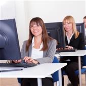 Group of diverse business people working in a support centre sitting at desks in front of computer monitors responding to email enquires